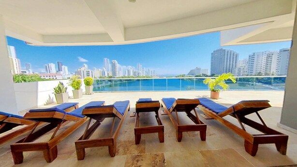 A rooftop lounge with wooden loungers and a city view. - apartamento de 2 habitaciones (Cartagena de Indias)