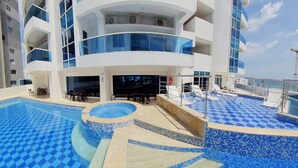 A modern hotel with a rooftop pool area, including a smaller pool and a larger pool with a checkered pattern. - apartamento de 2 habitaciones (Cartagena de Indias)