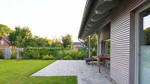 Et moderne hus med en terrasse, et træbord og en stol.
