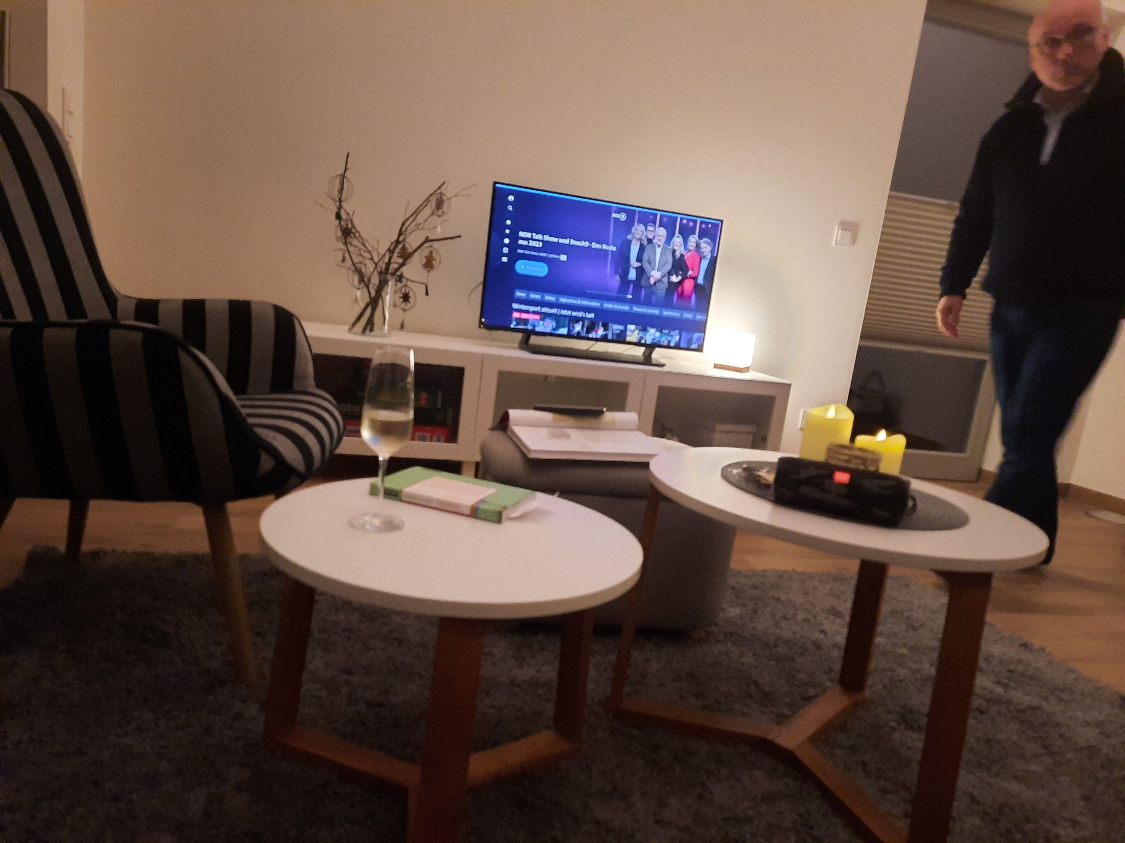 Un salon avec un téléviseur, un verre de vin, une petite table et une chaise.