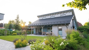 A modern house with a covered porch, a lawn, and various plants. - Vacation home Neukalen on Lake Kummerow - ideal for families and small groups (Neukalen)