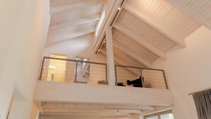 A multi-level interior with exposed wooden beams, a balcony, and a staircase. - Vacation home Neukalen on Lake Kummerow - ideal for families and small groups (Neukalen)