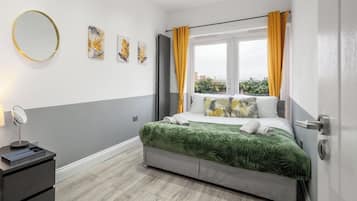 A modern bedroom with a bed, a bedside table, a mirror, and artwork on the wall.