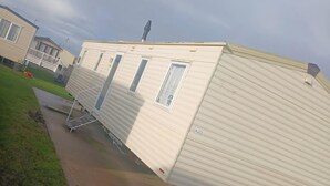 A mobile home with a flat roof, a small porch, and a single door. - Abi Caravan Sleeps 8 Lyons Winkups Holiday Park (Abergele)