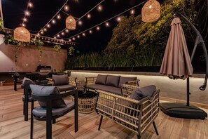 An outdoor seating area with wicker furniture, string lights, and a large umbrella. - Two Condesa Units with Rooftop Near Parque Mexico (Ciudad de México)