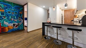 Une cuisine moderne avec un coin bar, un plancher en bois et une fresque murale colorée.
