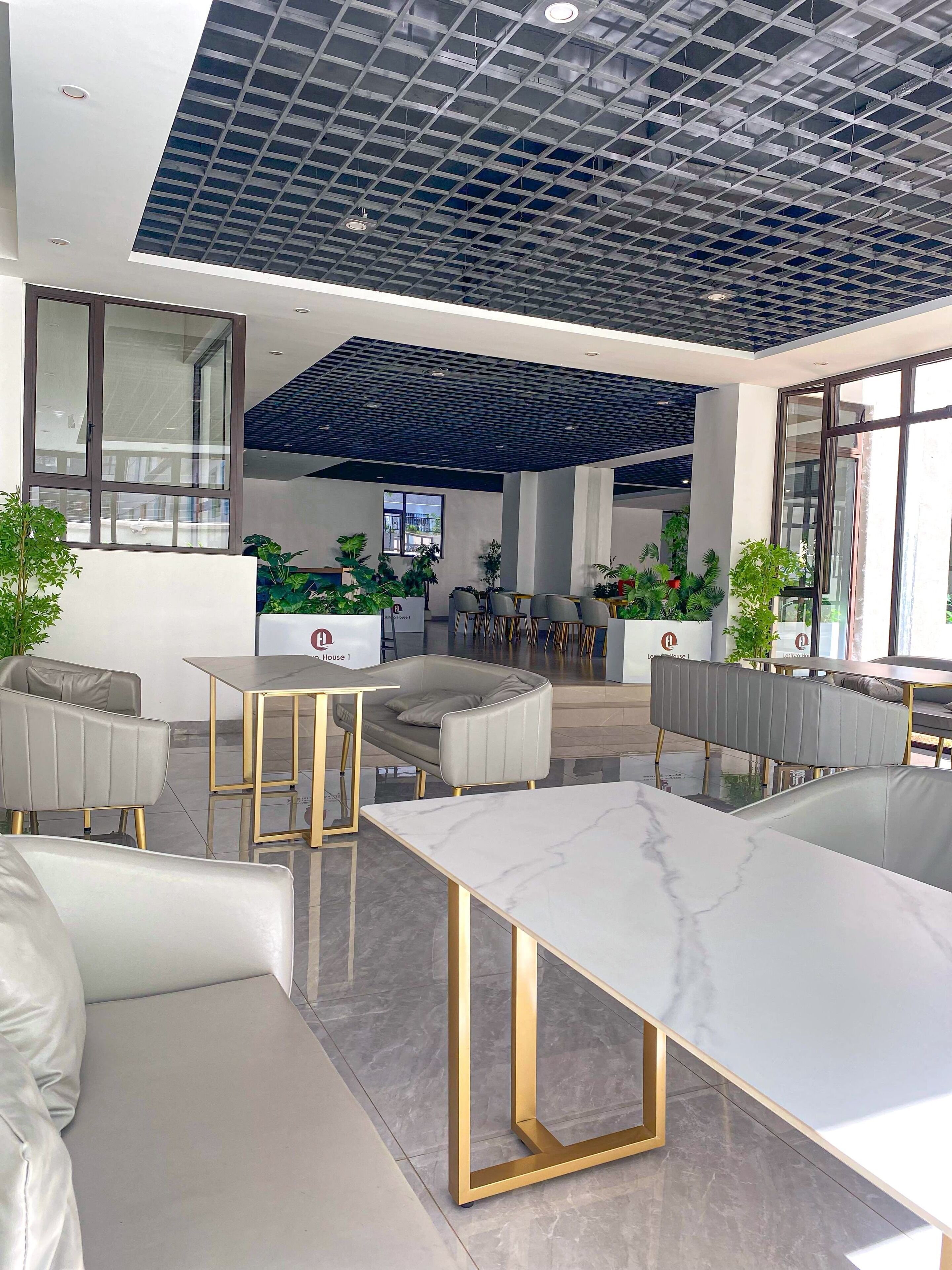 A modern office space with a high ceiling, glass partitions, and comfortable seating areas.