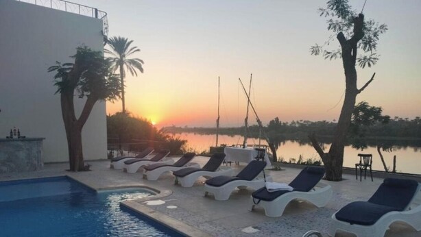 A swimming pool with lounge chairs and a sunset view. - Eyaru Palace  (Luxor)
