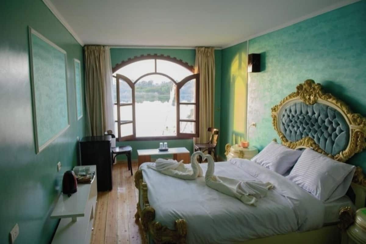 A room with a bed, a desk, a chair, and a window with a view.