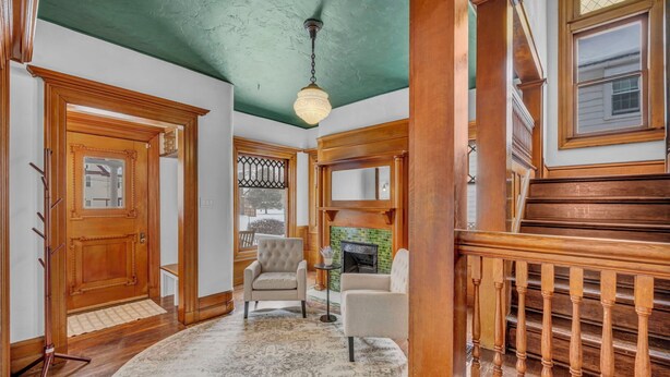 A hallway with a wooden door, a fireplace, and a staircase with a wooden railing. - Spacious 5-bedroom house with parking and everything you need in charming Elyria (Elyria)
