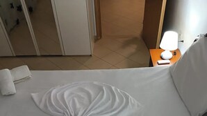 En pænt redt seng med hvide sengetøj og dekorative puder.