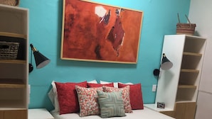 Ein Schlafzimmer mit einem Bett, einem großen abstrakten Gemälde und eingebauten Regale.