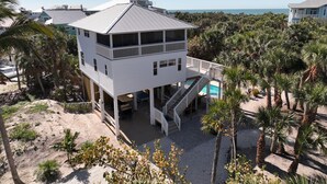Una casa de playa de dos pisos con balcón, piscina y vista al océano.