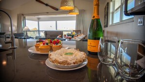 Una mesa de comedor con una botella de champán, dos copas y un postre con crema batida y fruta.