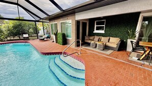 A swimming pool with a glass enclosure, a brick patio area, and a seating area with a sofa and chairs. - YOUR PRIVATE RETREAT NEAR SIESTA KEY BEACH! (Sarasota)