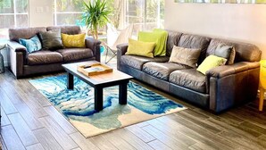 A spacious living room with two leather sofas, a coffee table, and a large window providing natural light. - YOUR PRIVATE RETREAT NEAR SIESTA KEY BEACH! (Sarasota)