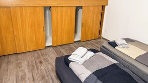 A compact room with a loft bed, wooden wardrobe, and a small seating area. - Ruhr Business Apartments Essen 7 beds Parking lot (Essen)