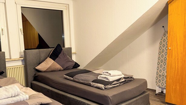 A compact bedroom with a bed, a sofa, and a wooden floor. - Ruhr Business Apartments Essen 7 beds Parking lot (Essen)
