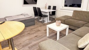 A modern living room with a sofa, a coffee table, a TV, and a dining area with chairs. - Ruhr Business Apartments Essen 7 beds Parking lot (Essen)