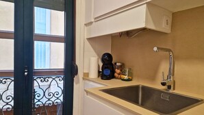 Une cuisine équipée d’un évier, d’une machine à café et d’un bocal en verre posé sur le plan de travail.