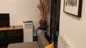 A hotel room with a bed, a desk with a computer, a radiator, and a framed picture on the wall.
