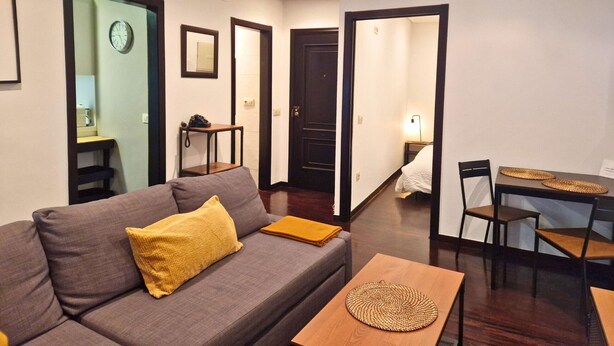 A living room with a sofa, a coffee table, and a dining area with chairs and a table.