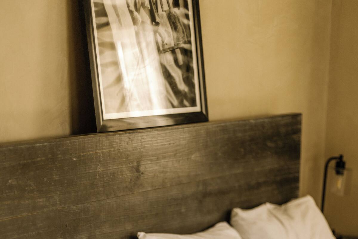Uma cama com roupa de cama branca e cabeceira de madeira.