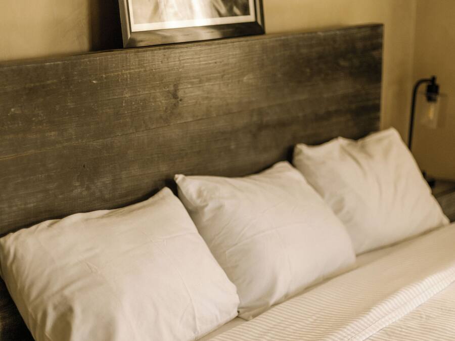 A bed with white bedding and a wooden headboard.