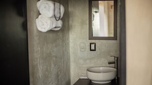 Un baño con un lavamanos grande, un espejo y toallas colgadas en la pared.