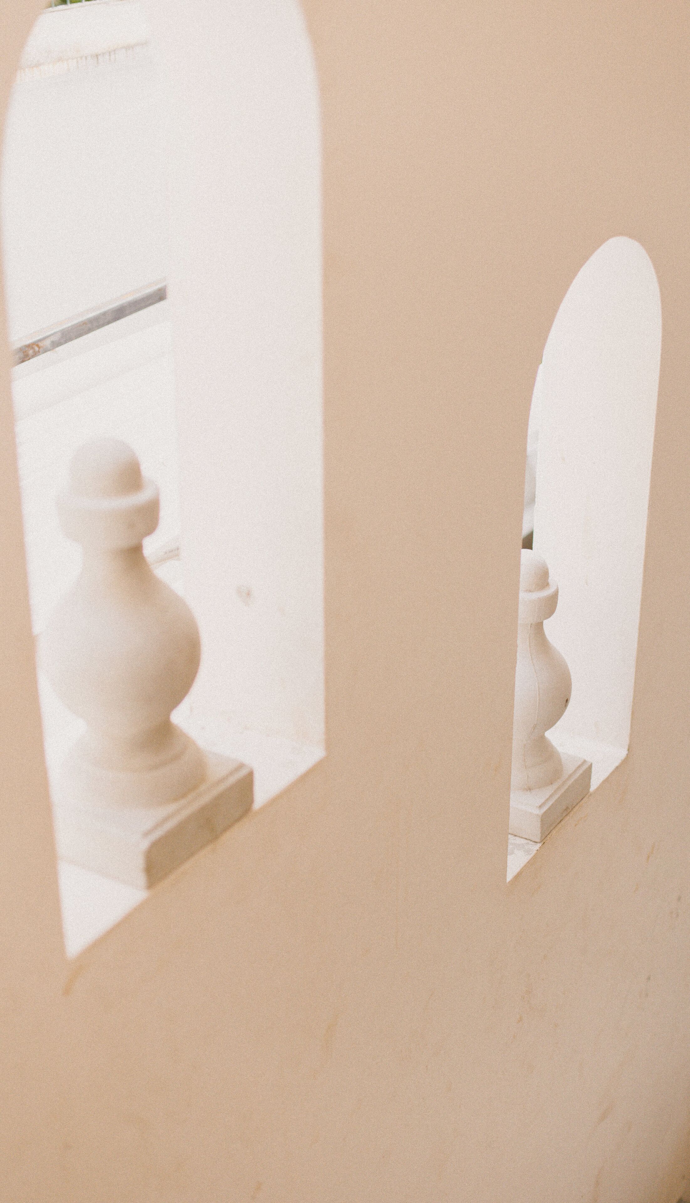 A mirror reflecting a white pedestal with a rounded top.