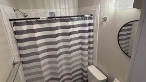 Un baño pequeño con cortina de ducha, inodoro y lavabo.