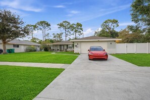 A residential driveway with a red car parked in front of a house. - Luxury Getaway In Naples | Pool & Elegant Remodel (Naples)