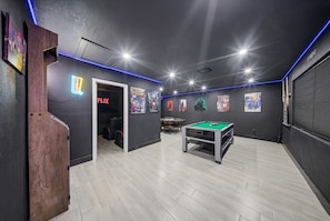 A room with a pool table, a door leading to a seating area, and a neon sign for Netflix. - Luxury Getaway In Naples | Pool & Elegant Remodel (Naples)