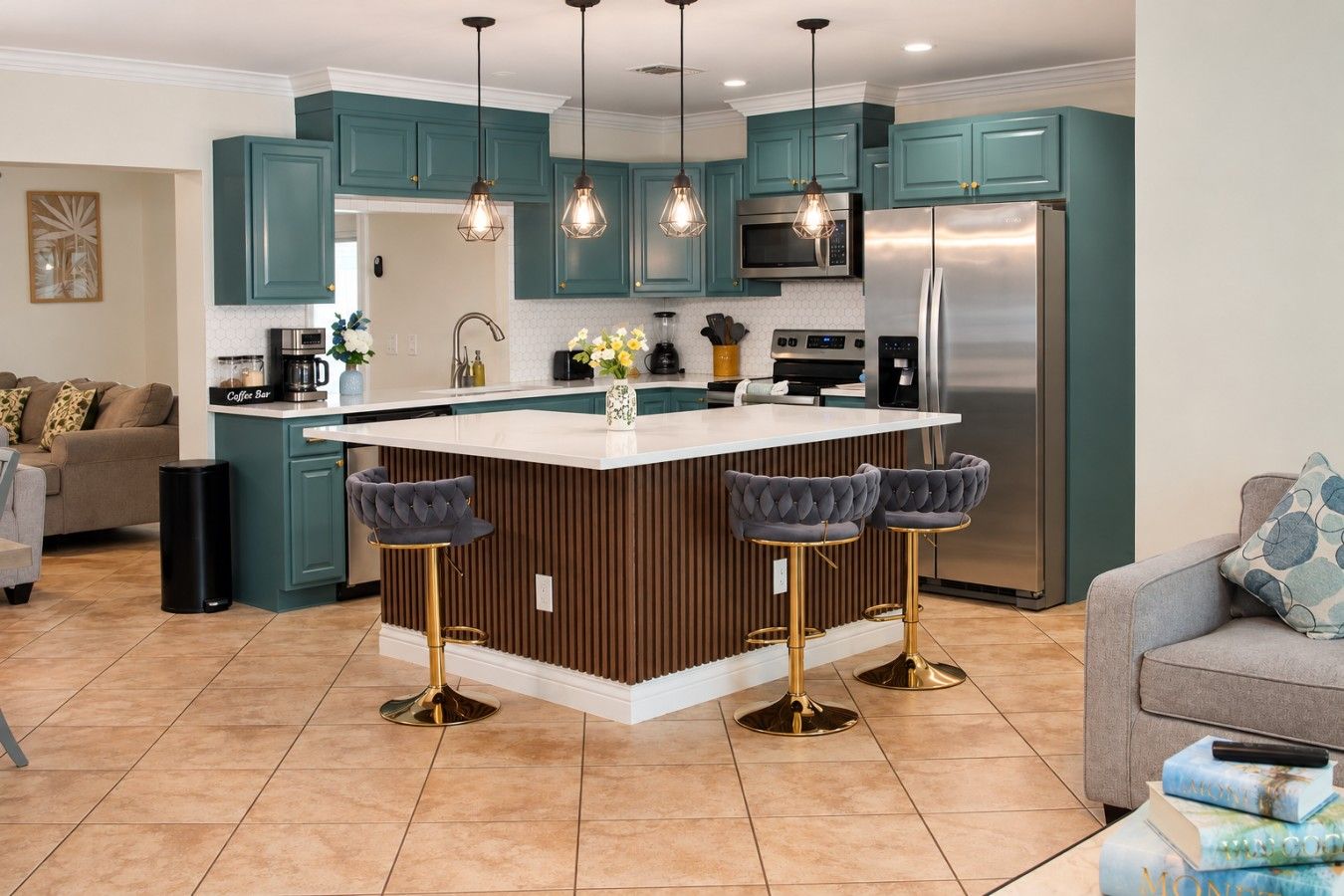 Une cuisine moderne avec des armoires de couleur turquoise, un réfrigérateur en acier inoxydable et un îlot central doté de tabourets de bar.