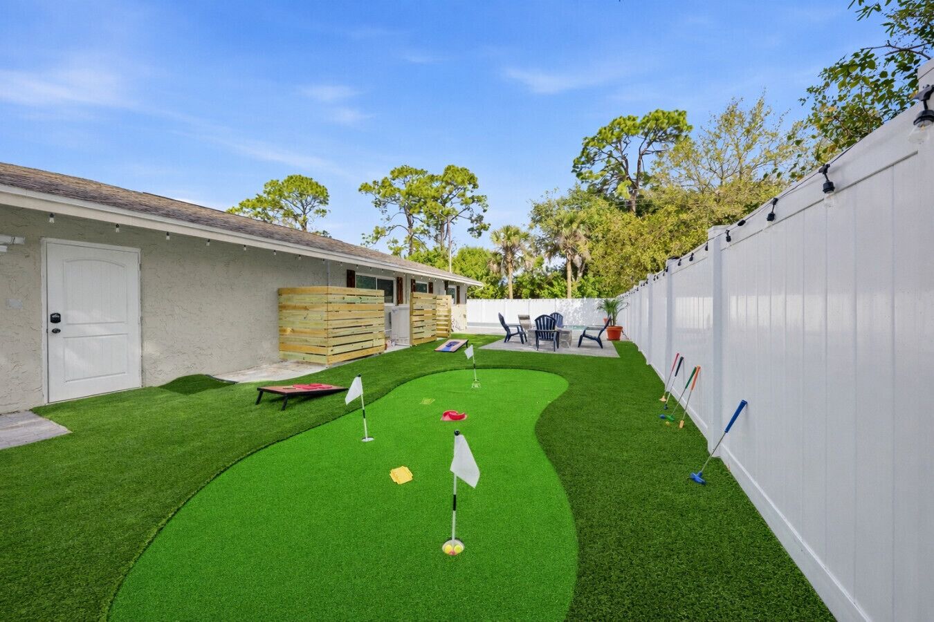 A backyard with artificial grass, a putting green, and a patio area with outdoor furniture.