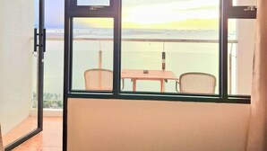 Ein Balkon mit Tisch und Stühlen mit Blick auf ein Gewässer und entfernte Landschaft.