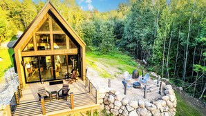 A wooden cabin with a deck, large windows, and outdoor seating. - Modern Adirondack Getaway (Malone)