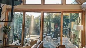 A spacious interior with a high ceiling, large windows, and a staircase. - Modern Adirondack Getaway (Malone)
