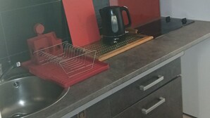 A kitchen with a sink, a red cutting board, a black kettle, and a coffee maker. - Studio 16 mcarré kicnetteet frigo compartiment congelateur micro ondes (Perpignan,)