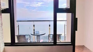 Una habitación con balcón que da a una masa de agua y una costa lejana.