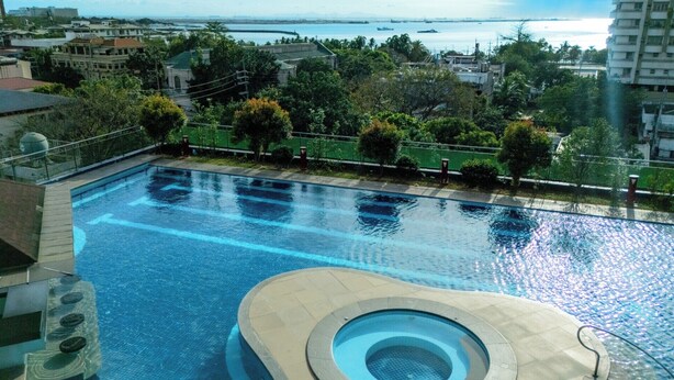 Una piscina con un jacuzzi circular, rodeada de vegetación y con vista a un cuerpo de agua.