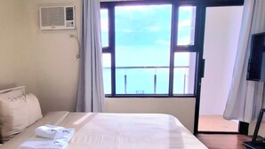Una habitación de hotel con una cama, un televisor y una ventana con vista al mar.