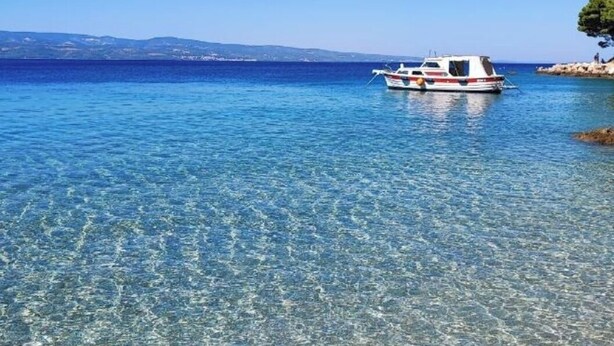 A boat on clear blue water with a distant shoreline. - Lux Apartment Nina&Martina new 2025 (Split)