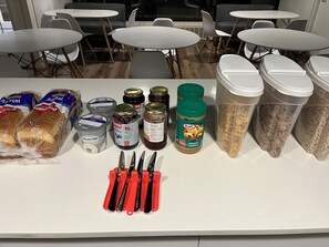 A kitchen counter with various food items, jars of preserves, and a knife block. - Pod-Inn Hotel (Toronto)