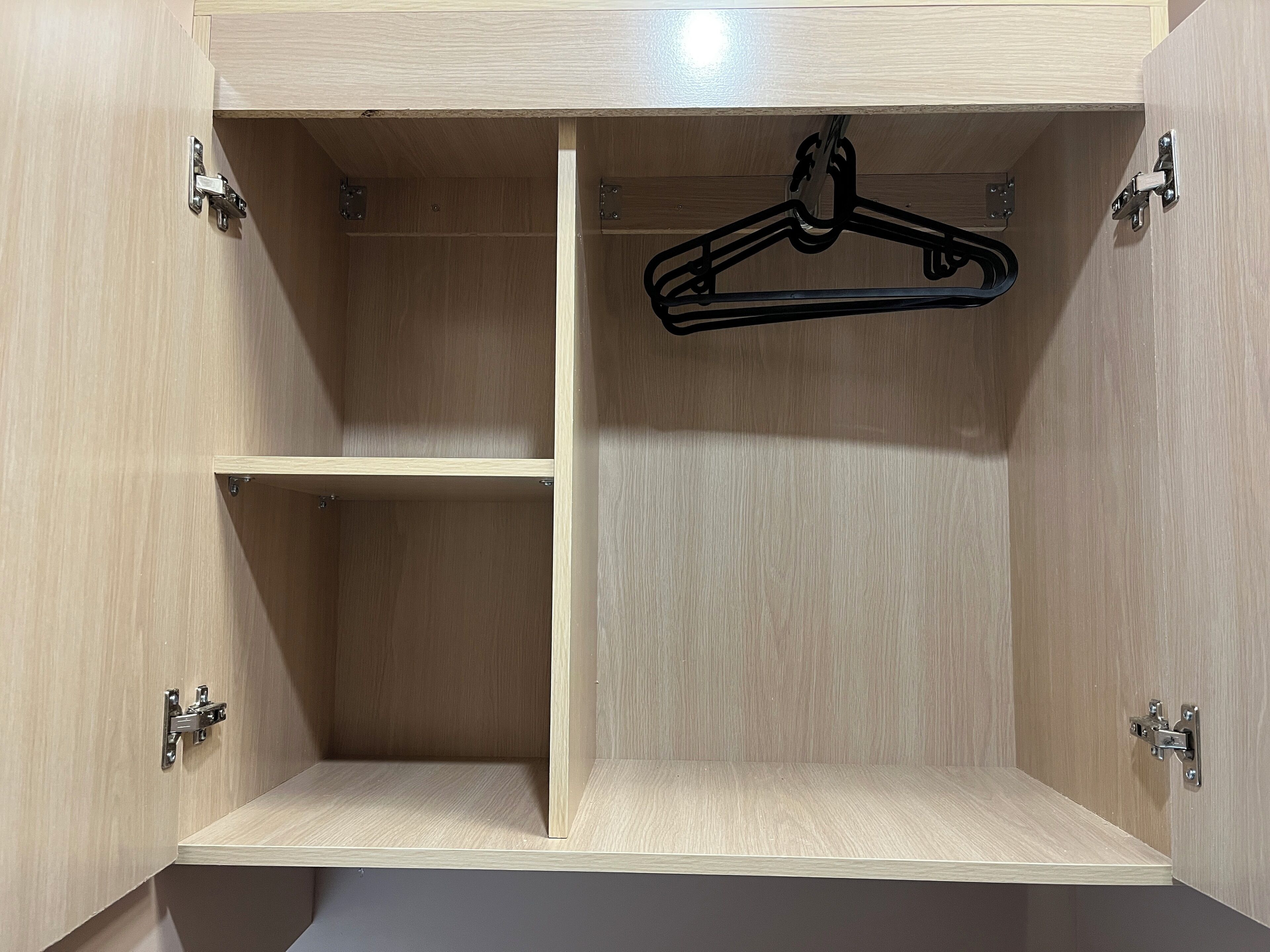 Une armoire en bois avec deux étagères ouvertes et une tringle pour suspendre les vêtements.