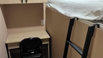 Een kleine kamer met een stapelbed, een bureau en een stoel.