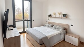 A modern bedroom with a bed, bedside tables, a desk, and a large window. - Bed & Bergamo Holiday Home in neighborhood surrounded by greenery, 5km from the airport! (Bergamo)