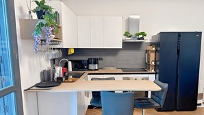 A modern kitchen with white cabinets, a black refrigerator, and a wooden island with bar stools. - Bed & Bergamo Holiday Home in neighborhood surrounded by greenery, 5km from the airport! (Bergamo)