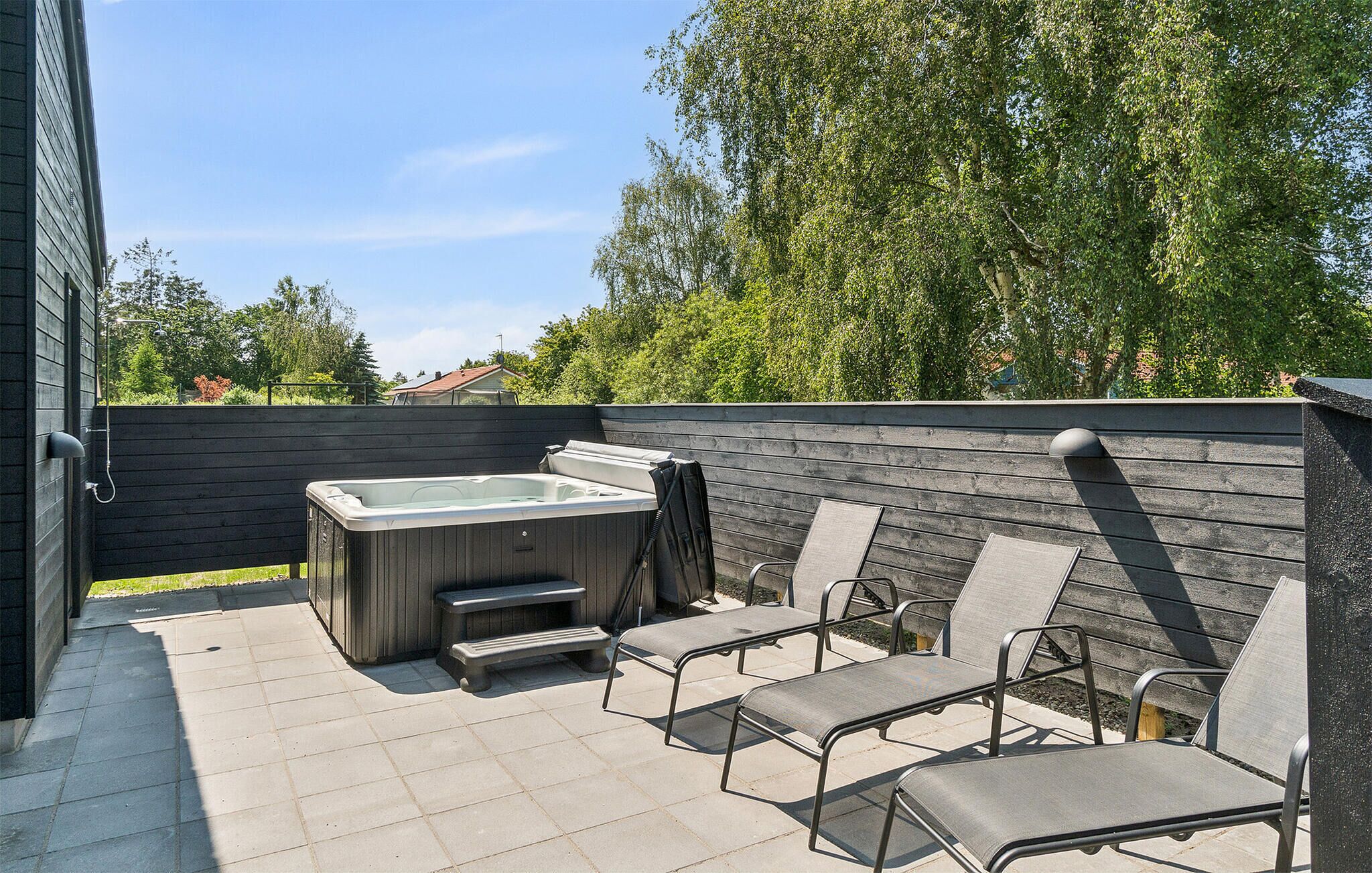 An outdoor patio with a hot tub, lounge chairs, and a wooden deck.