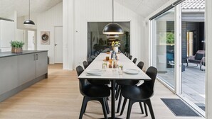 Ett modernt matområde med ett långt bord, svarta stolar och hängande lampor.